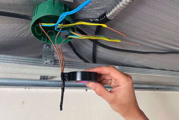 Applying black 3M Scotch Vinyl Electrical Tape Super 33+ for wire insulation inside a junction box.